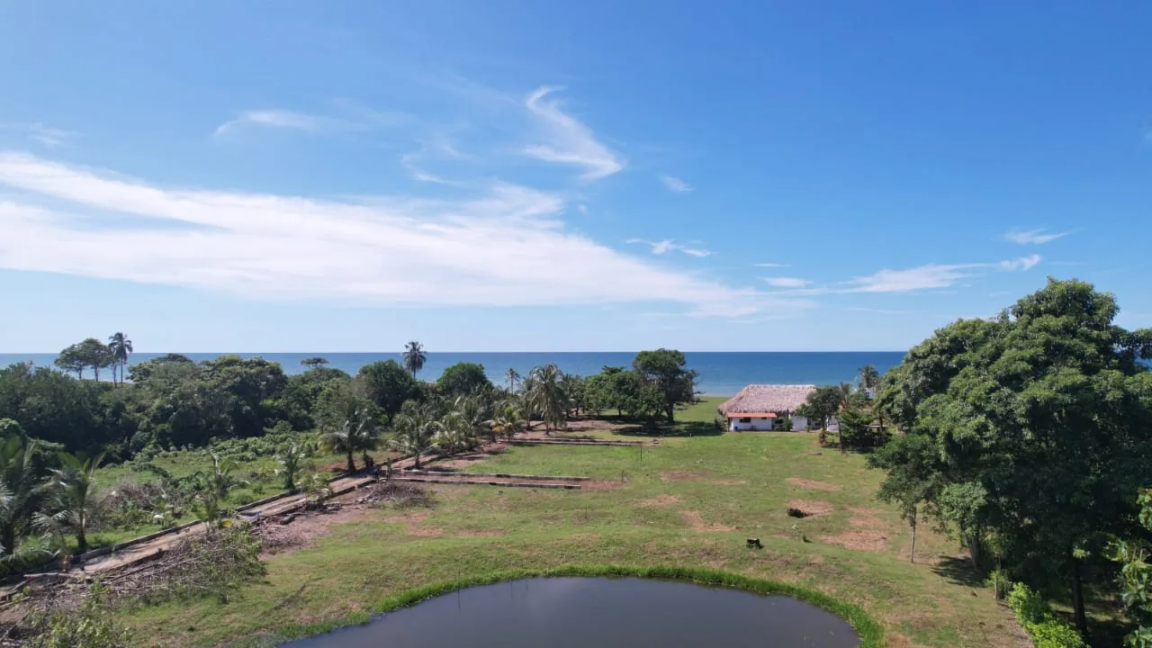 Vista de dron desde la laguna hacia el mar, con la villa tradicional y los trazos de la vía